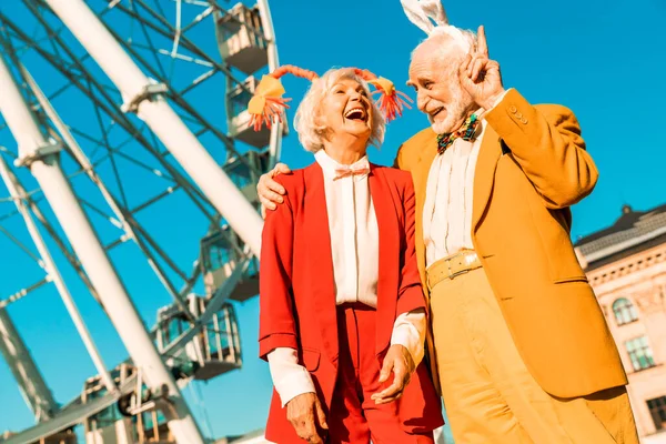 Funny elderly couple walking near ferris wheel — Stock Photo, Image