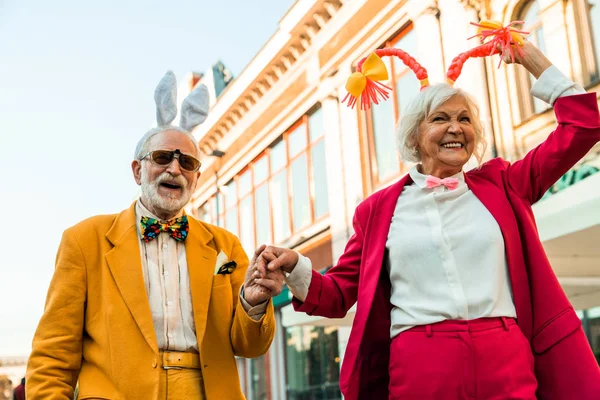 Χαμογελώντας ηλικιωμένο ζευγάρι κρατώντας τα χέρια στην πόλη — Φωτογραφία Αρχείου