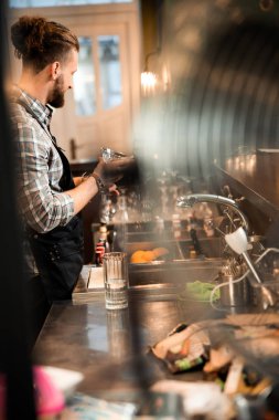 Sakallı barmen tezgahın önünde duruyor.