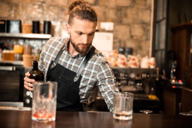 Yakışıklı barmen elinde açık bir şişe tutuyor.