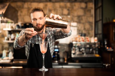 Erkek sakallı barmen süslü kokteyl yapıyor.