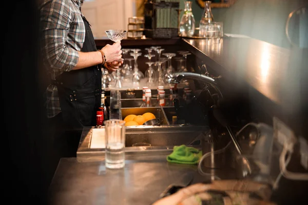 Young male bartender holding glass in his hands — Stock Photo, Image