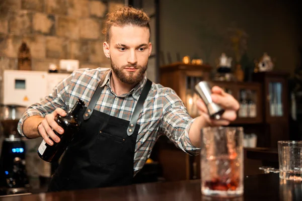 Genç barmen taze alkollü içecek dolduruyor.