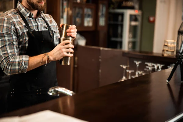 Joven camarero haciendo cóctel en la coctelera en el mostrador del bar — Foto de Stock