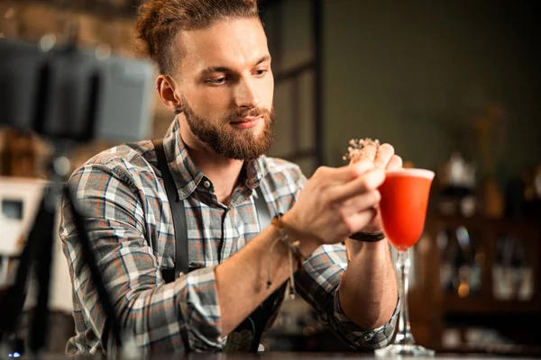 Sonriente barbudo camarero decorando vaso de bebida naranja — Foto de Stock