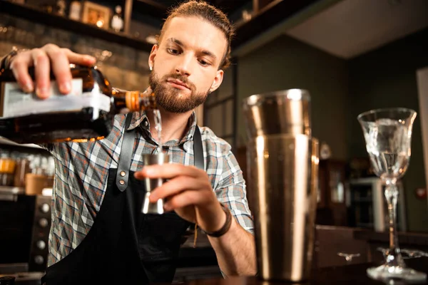 Mladý barman drží v ruce láhev alkoholu. — Stock fotografie