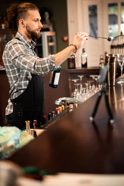 Mladý vousatý barman stojí a pije — Stock fotografie