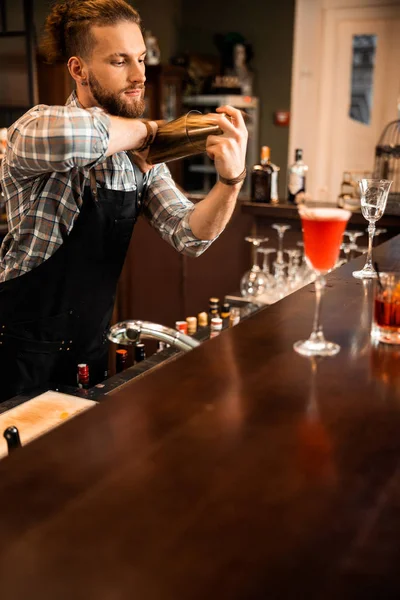 Joven barman mezclando cóctel mientras trabaja en el bar — Foto de Stock