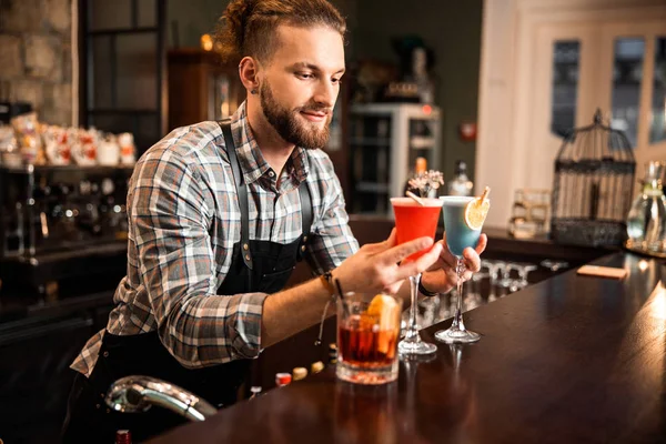 Barman sorridente está segurando dois coquetéis coloridos — Fotografia de Stock