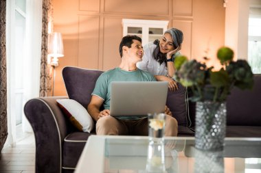 Evde karısına bakan gülümseyen yetişkin bir adam.