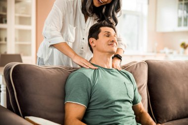 Gülümseyen olgun kadın kocasına masaj yapıyor.