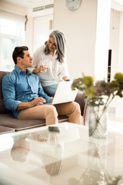 Mutlu yetişkin çift evde dinlenirken konuşuyor.