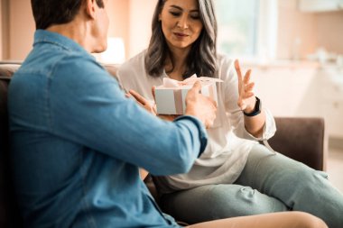 Yetişkin bir adam evde karısına hediye veriyor.