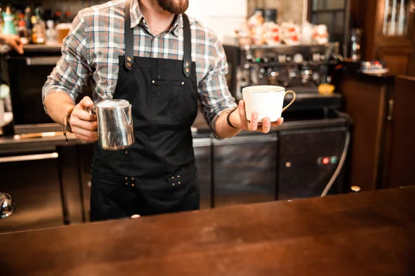 Erkek barista kahveye süt döküyor. — Stok fotoğraf