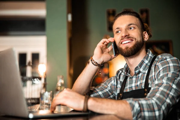 Feliz joven barman trabajando con el ordenador portátil en el pub — Foto de Stock