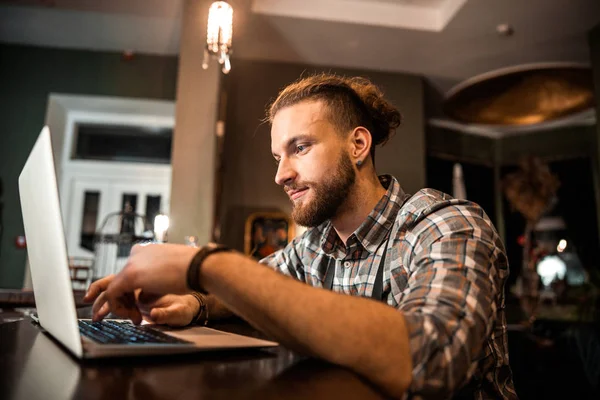 Mosolygó szakállas férfi ül és dolgozik laptop — Stock Fotó
