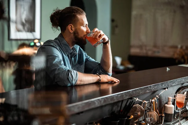 El joven está sentado en el mostrador del bar adentro. — Foto de Stock