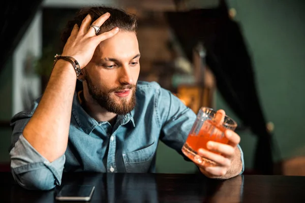 Joven sentado con bebida alcohólica en el mostrador del bar — Foto de Stock
