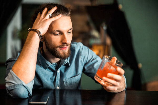 Young guy sitting with alcoholic drink at bar counter