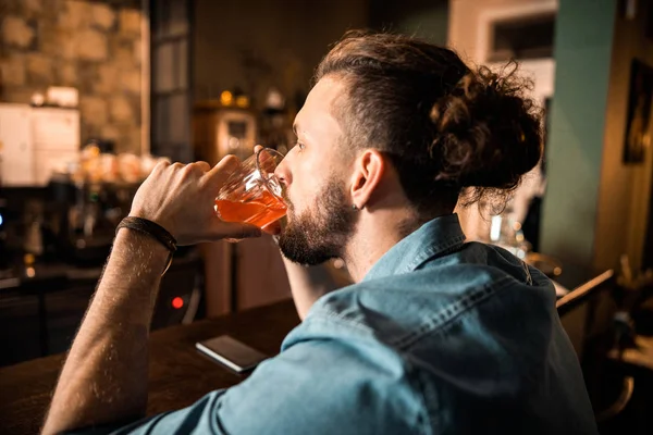 Hombre barbudo sentado en el mostrador del bar y bebiendo — Foto de Stock