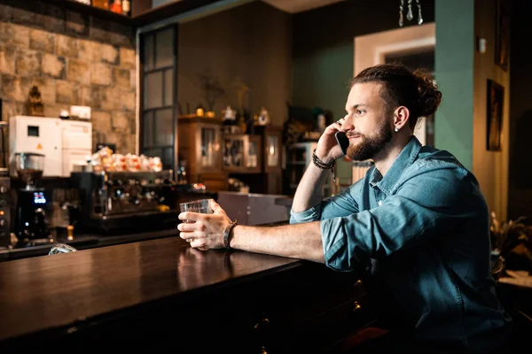 Улыбающийся молодой парень разговаривает по мобильному телефону в баре — стоковое фото