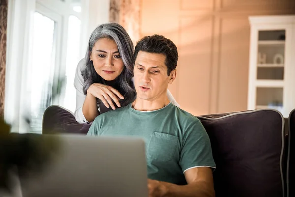 Glad vuxen par använder laptop i vardagsrummet — Stockfoto