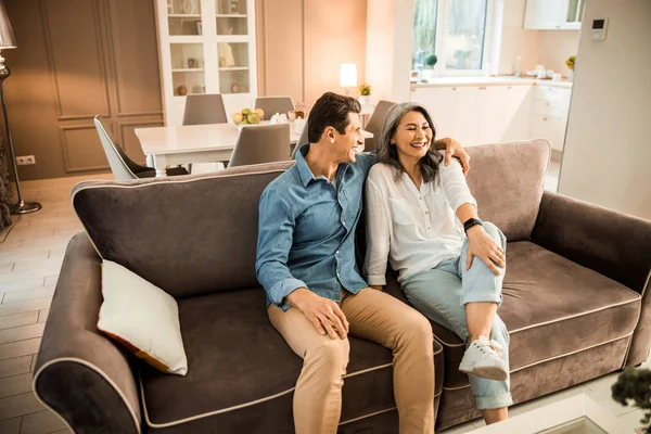 Sorrindo homem adulto abraçando mulher bonita na sala de estar — Fotografia de Stock