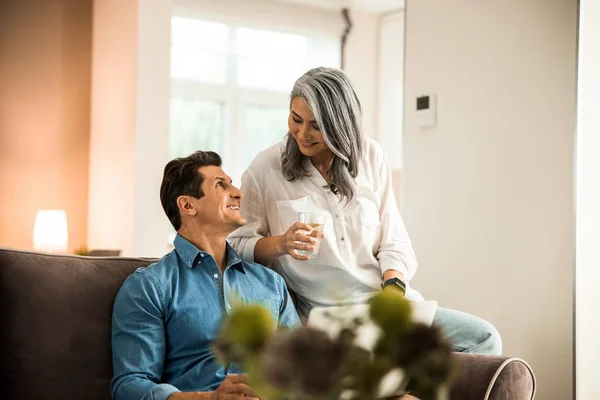 Счастливый взрослый мужчина смотрит на свою жену в гостиной — стоковое фото