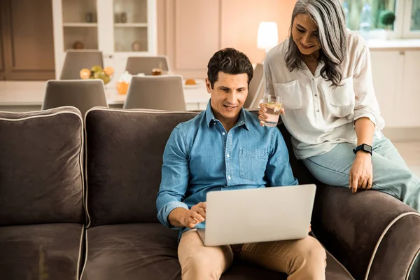 Sorridente coppia adulta guardando lo schermo del computer portatile in camera — Foto Stock