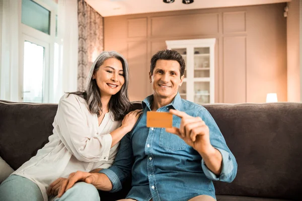 Felice uomo adulto e donna con carta di credito in camera — Foto Stock
