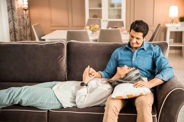 Wanita dewasa yang bahagia berbaring di sofa dan melihat pria di rumah. — Stok Foto