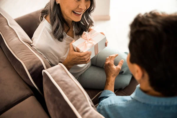 Sonriente pareja enamorada sosteniendo presente en las manos en casa —  Fotos de Stock