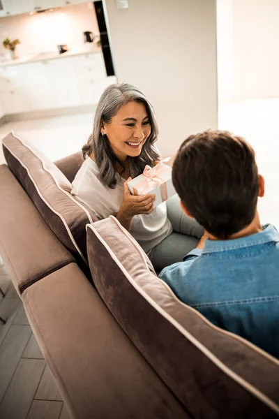 Wanita cantik yang bahagia duduk dengan hadiah di sofa — Stok Foto