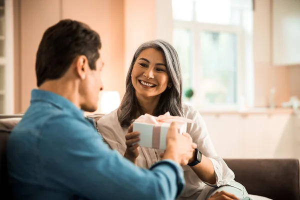 Sonriente mujer adulta disfrutando de regalo del hombre en la habitación — Foto de Stock