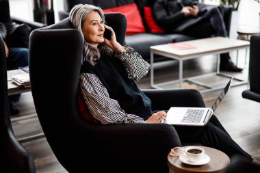 Ofis lobisinde telefon konuşması yapan bir kadın.