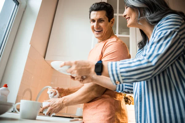 Sorridente signora aiutare per l'uomo in cucina — Foto Stock