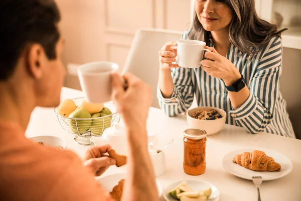 Glückliche hübsche Dame hält Tasse in der Hand, während sie Mann ansieht — Stockfoto