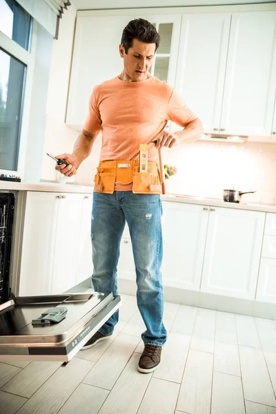 Erkek işçi bulaşık makinesini tamir edecek. — Stok fotoğraf