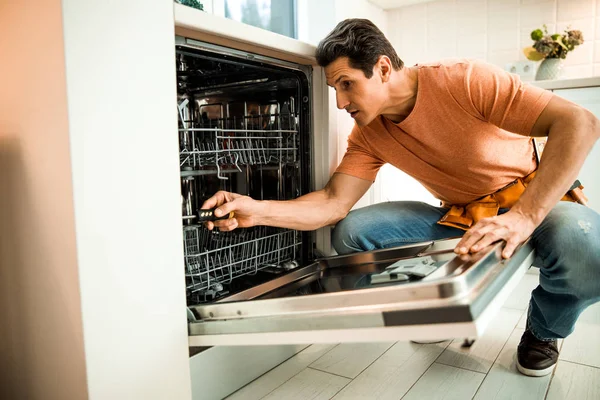 Male worker using screwdriver to repair dishwasher — Stock Photo, Image