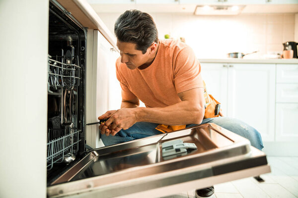 Man is repairing appliances in the kitchen