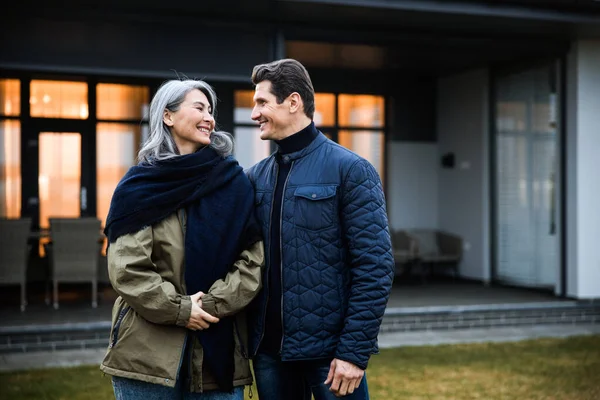 Χαμογελώντας ώριμος σύζυγος στέκεται με τη γυναίκα του στην πίσω αυλή του σπιτιού — Φωτογραφία Αρχείου