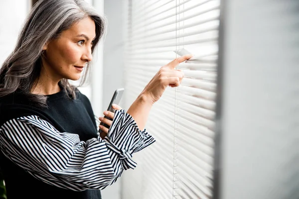 Curious lady looking out of the window stock photo