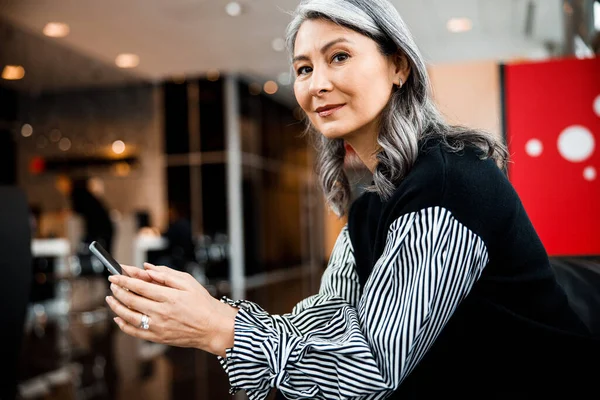 Mature lady with smartphone looking glad stock photo — Stock Photo, Image