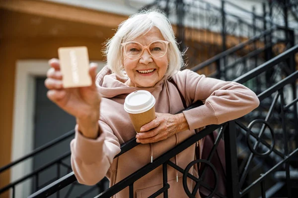 Счастливая пожилая дама с кофе на улице — стоковое фото