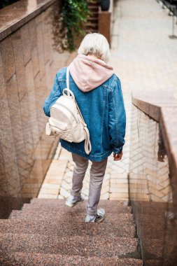 Yaşlı bir kadın açık hava fotoğraflarıyla aşağıya iniyor.