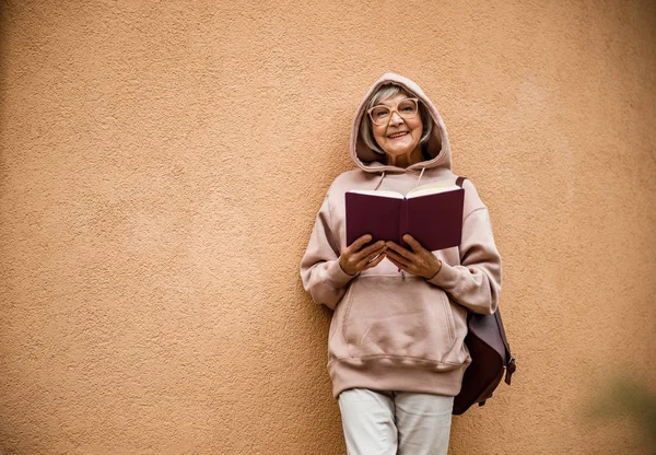 Радостная пожилая женщина с фотоальбомом на открытом воздухе фото — стоковое фото