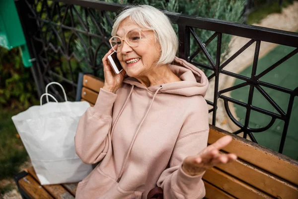 Веселая пожилая женщина делает звонок в парк фото — стоковое фото