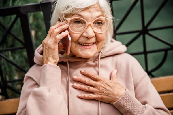 Радісна стара леді говорить на мобільний телефон на відкритому повітрі стокове фото — стокове фото
