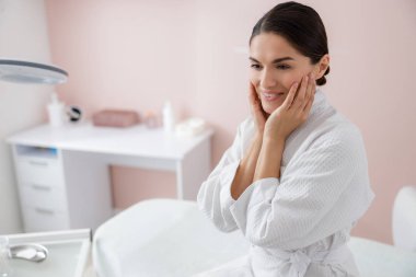 Neşeli genç bir kadın ellerini yanaklarına koyuyor.