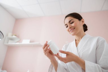 Neşeli güzel bayan elinde bir şişe vitamin tutuyor.
